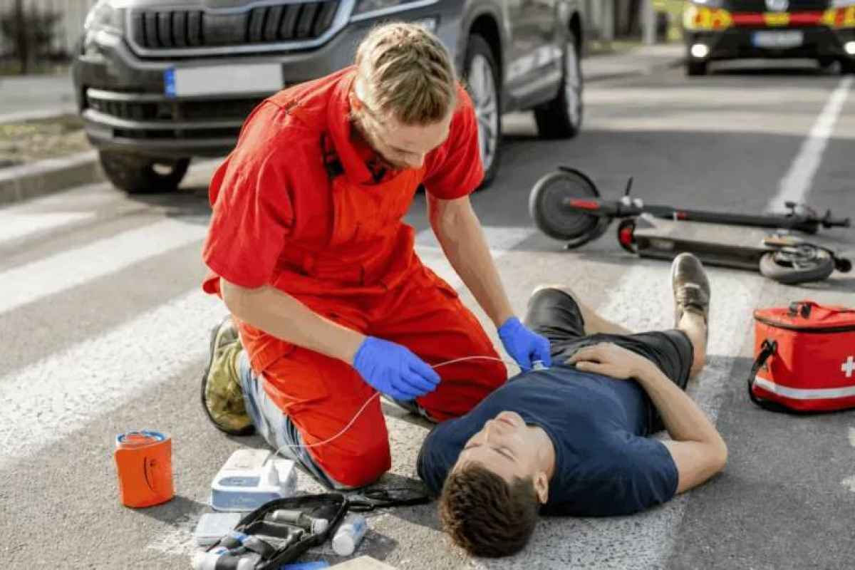 Gelbėtojas teikia pirmąją pagalbą vyrui ant gatvės perėjos